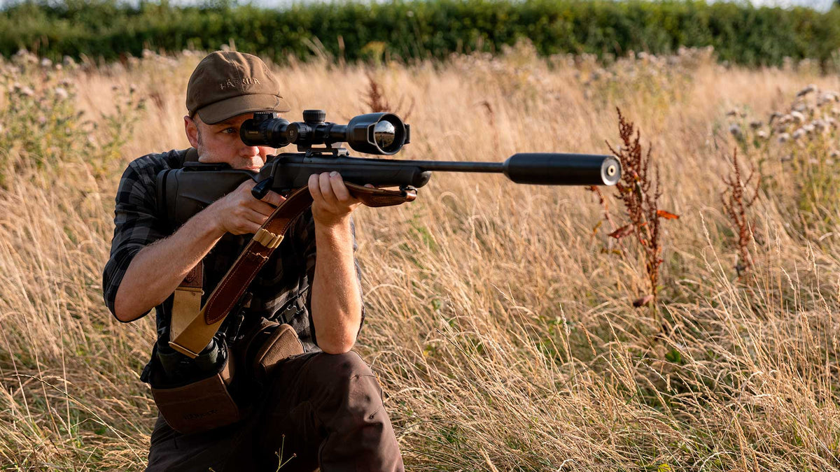 Chasseur en position de tir à genou dans les hautes herbes, carabine équipée de la lunette thermique Pulsar Thermion 3