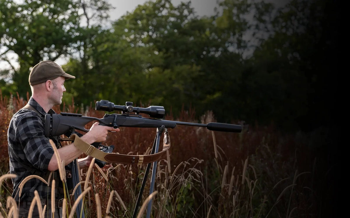 Chasseur à l’affût dans les hautes herbes avec une carabine équipée de la lunette thermique Pulsar Thermion 3